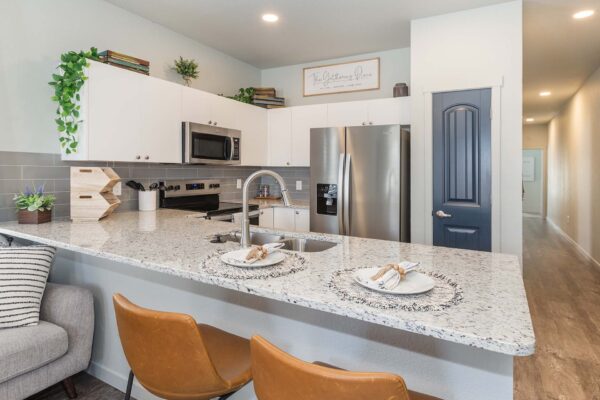 Cottages at Woodmen Heights apartment kitchen with breakfast bar, light counters, and stainless steel appliances.