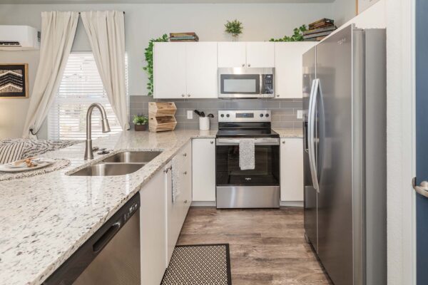 Cottages at Woodmen Heights apartment kitchen with light counters, white cabinets, and stainless steel appliances.