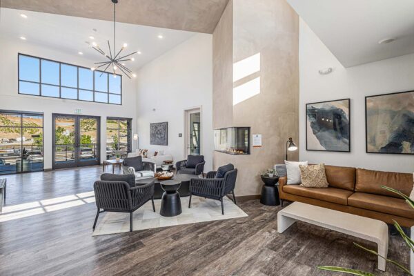The Preserve at Mesa Creek clubhouse with plush seating, fireplace, large windows, and large light fixture.
