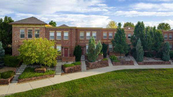 Enclave Rigden Farm exterior with brick construction and large green trees.